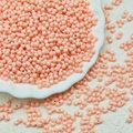 Macro shot of 3x6mm pale peach twin-hole glass seed beads for DIY jewelry making - Soft Pink