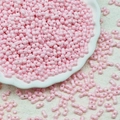 Macro shot of 3x6mm pink dual-hole glass beads for DIY jewelry making in a decorative dish - Light Pink