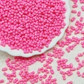 Macro detail of rose pink bow-tie glass beads for DIY jewelry making in a white ceramic dish - Deep Pink