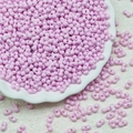 Macro shot of 3x6mm pink dual-hole peanut glass beads in a decorative white dish - Light Purple