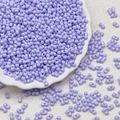 Macro detail of lavender double-hole glass beads for DIY jewelry on white porcelain plate - Cool Purple