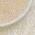 Macro shot of 3mm iridescent cream glass seed beads on a white porcelain dish and leather - Beige