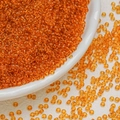 Macro shot of transparent orange 3mm glass seed beads for DIY jewelry making and crafts - Orange