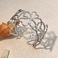 Armreif mit hohlen Blumenmustern aus Edelstahl auf Sand mit Seestern und Muscheln - Silber