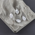 Makroaufnahme von versilberten Zirkonia-Anhängern in Tropfenform mit Krallenfassung auf Stein - Transparent Weißer Stil (M110601)