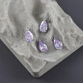 Nahaufnahme von lavendelfarbenen Tropfenanhängern mit Silberfassung auf grauem Stein - Lavendel Stil (M110603)