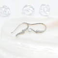 Silver lightning bolt earrings with pavé zircons placed on a white pearl shell background - White Gold