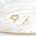 Macro shot of gold heart-shaped toggle clasp with textured finish on shell backdrop - Heart / Gold