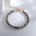 Dalmatian Jasper beaded bracelet with gold lobster clasp and round charm on white surface - Dalmatian Jasper Bracelet
