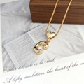 Macro detail of gold C letter pendant with colorful gemstones on dark wood jewelry box - Letter C