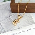 Macro detail of gold heart pendant with colorful zircon encrusted letter M on wood - Letter E