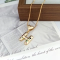 Close-up of golden letter H pendant with colorful stones and heart on a gold necklace - Letter H