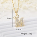 Macro view of 18k gold plated letter M pendant with crown and zircon stones - Gold M