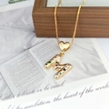 Close-up of golden letter M pendant with colorful zircon stones and heart clasp - M