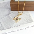 Detail view of golden N-shaped pendant with multicolor zircons and heart clasp - Letter N