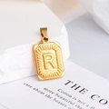 Macro-opname van een gouden rechthoekige hanger met letter R en zonnestraalmotief - Letter R