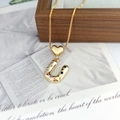 Close-up of golden necklace featuring a heart charm and multi-color zircon letter U pendant - Letter U