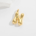 Detailed macro view of a 3D bubble style golden letter H pendant on a white stone background - Letter N