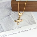 Detail of gold letter X heart pendant with multicolor zircon stones on a wooden box - Letter X