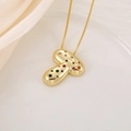 Détail d'un pendentif champignon doré avec strass colorés sur un tissu de soie doux - Lettre T