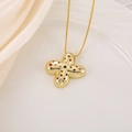 Gros plan du pendentif croix dorée avec zircons colorés sur fond de tissu en soie - Lettre X