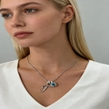 Macro view of crystal letter F and round blue gemstone pendant on a fine silver necklace - Silver T