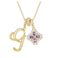 Macro detail of gold necklace with letter G pendant and purple zircon clover charm - Gold G