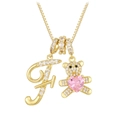 Macro view of gold teddy bear charm with pink heart gemstone and letter F pendant - Letter F / Gold