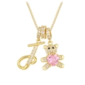 Macro detail of golden bear necklace with letter J and pink heart-shaped crystal stone - Letter J / Gold