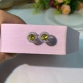 Vue macro d'une boucle d'oreille halo ronde avec pierre jaune-vert et zircons - Or
