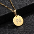 Vista macro del colgante de letra N dorada con pavé de circonitas y cadena cruzada - Letra N