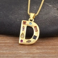 Detalle macro del collar con colgante letra D dorado y piedras circonitas de colores - Letra D