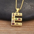 Detalle macro del colgante letra E dorado con piedras de circonia multicolor - Letra E
