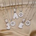 Detail der silbernen Buchstaben-Halsketten mit Zirkonia auf champagnerfarbenem Satin - Baguette und Blumen Kombi / Buchstabe A