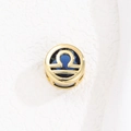 Detalle macro del colgante Libra dorado con circón azul oscuro y diseño calado - Libra