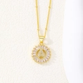 Macro shot of 18K gold letter A pendant with baguette zircons on a beaded chain - Floral Medallion with Satellite Chain (A)