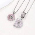 Detail of silver D initial pendants with pink zirconia and iced out crystal setting - Silver D