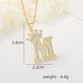 Vue macro du collier pendentif lettre M avec couronne dorée et zircons étincelants - Pendentif Couronne Lettre M Doré / Or