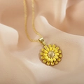 Collier tournesol doré avec pétales en émail jaune posé sur un tissu pêche délicat - Jaune