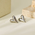 Polished silver heart stud earrings in minimalist 3D design on a warm stone background - Silver Heart Stud Earrings (HC3165)