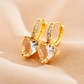 Macro detail of gold heart earrings with zircon micro-paving on elegant silk background - White