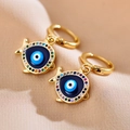 Macro view of gold fish-shaped earrings with colorful zircon and evil eye enamel detail - Fish Shape Style / Gold/Multicolor