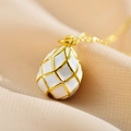 Detailed close-up of a Faberge-style white enamel egg pendant with gold lattice pattern - White