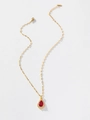 Detailed view of a gold teardrop pendant with red gemstone and halo of white diamonds - Red