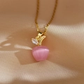 Macro shot of pink cat eye stone apple pendant with gold chain on silk fabric - Red