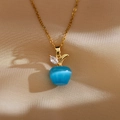 Detailed view of blue cat eye stone apple pendant with gold chain on satin fabric - Blue