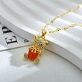 Detalle de un colgante de oso dorado con microcirconitas y una gema roja en forma de corazón - Rojo