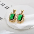 Macro detail of rectangle emerald-cut green crystal earrings with halo zircons and gold plating - Gold Green Stud Earrings