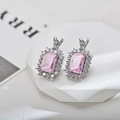 Macro view of rectangular pink zircon stud earrings with silver halo setting on a stand - Silver Pink Stud Earrings