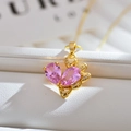 Detalle macro del colgante dorado con circonitas rosas sobre soporte de cuero blanco - Dorado